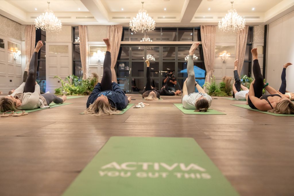 Kelas orang melakukan yoga di atas tikar hijau dengan candelier di atas kepala