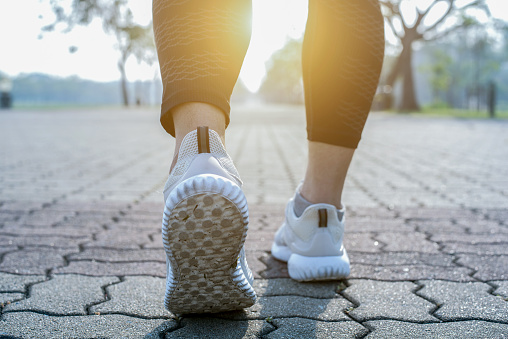 Kaki pelari berlari di atas jalan dekat dengan kasut.