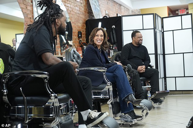 Calon presiden Demokrat Naib Presiden Kamala Harris, tengah, duduk dalam perbualan dengan lelaki kulit hitam di kedai gunting rambut Philly Cuts, 27 Okt. 2024, di Philadelphia