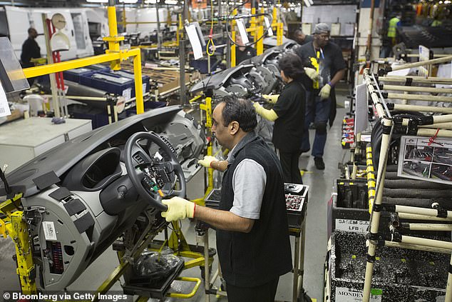 Pekerja memasang papan pemuka dan stereng untuk trak Vauxhall Vivaro di barisan pengeluaran di kilang Luton Vauxhall.