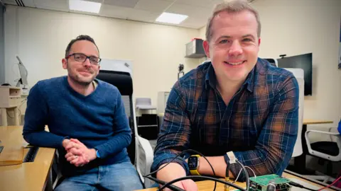 Dr Matt Ash dan Dr James Brown bekerja pada papan litar elektrik di pejabat mereka di Cambridge.