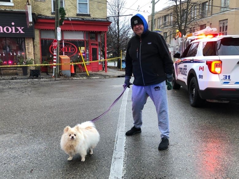 Seorang lelaki dan seekor anjing berdiri di hadapan kereta polis dan merosakkan bangunan.