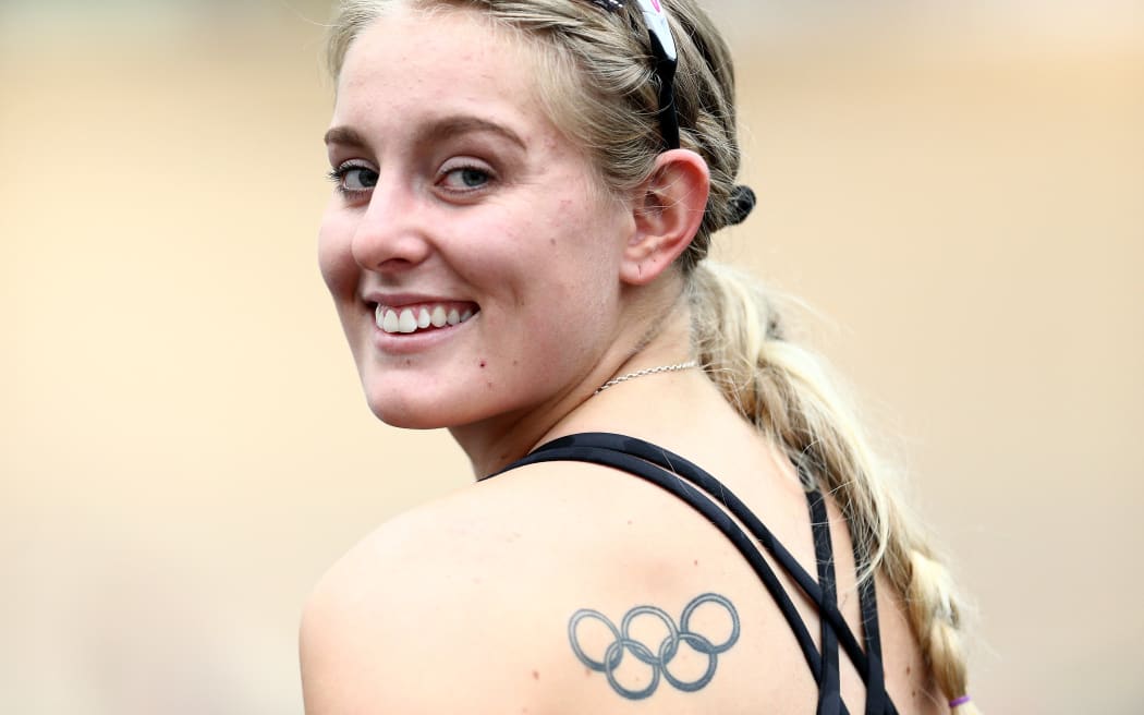 Foto Olivia Podmore memandang ke arah jurugambar dari atas bahunya dan tersenyum. Dia memakai tank top hitam dan mempunyai tatu cincin Olimpik pada bilah bahunya.