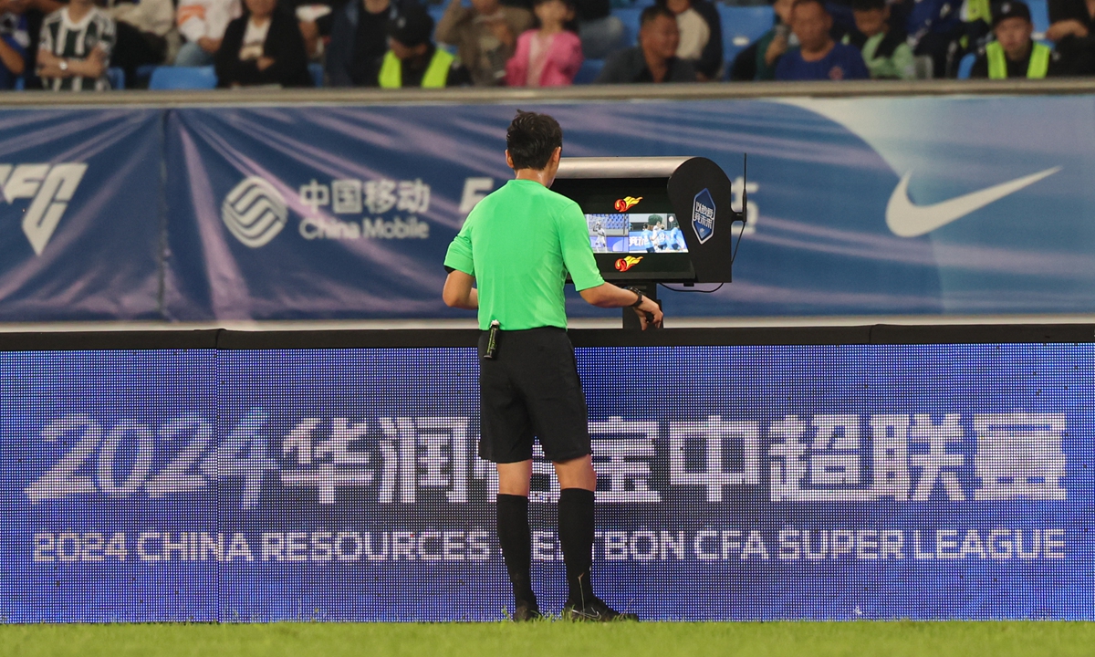 Pengadil melihat monitor tepi padang sebelum membuat keputusan semasa perlawanan bola sepak di Cangzhou, Wilayah Hebei, China Utara. Foto: IC