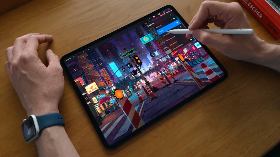   Seseorang menggunakan Pensil Apple untuk menggambarkan pemandangan jalanan malam pada iPad Pro OLED. 